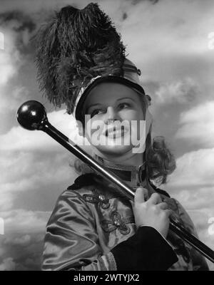 Photo de tête d'une majorette contre un fond nuageux portant sa casquette shako qui a un panache ou pompon comme décoration de son bâton sous son bras Banque D'Images