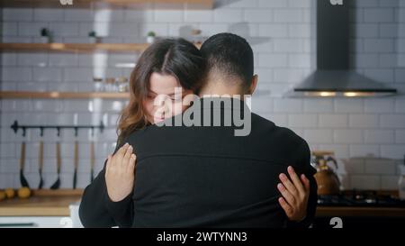 Vue arrière de l'homme embrassant son petit ami. Belle femme embrassant son amant dans la cuisine. Gros plan moyen câlins couple bien-aimé jeune Banque D'Images