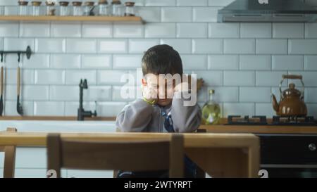 Enfant bouleversé assis dans la cuisine seul à la maison. Solitaire offensé écolier se sentant déçu intimidé, stressé assis à table. Problème des écoliers Banque D'Images