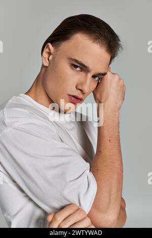bon débonair jeune homme regardant dans un t-shirt élégant élégant regardant la caméra sur fond gris Banque D'Images