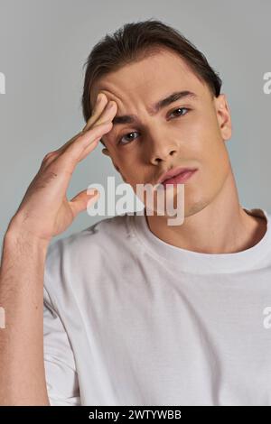 bon débonair jeune homme regardant dans un t-shirt élégant élégant regardant la caméra sur fond gris Banque D'Images