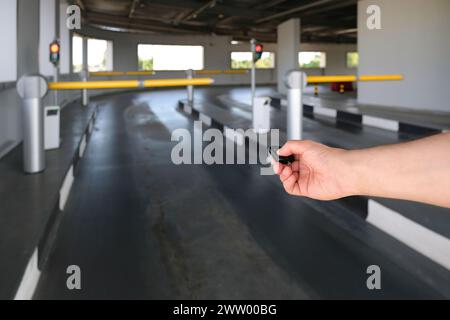 Une main utilisant une télécommande ouvre une barrière automatique dans un parking. Lever la barrière lorsque vous quittez le parking à l'aide de la télécommande Banque D'Images