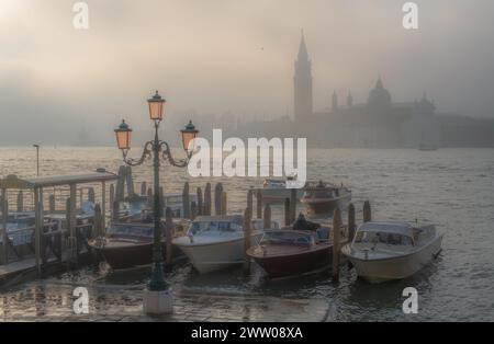 Gondoles à Venise au lever du soleil dans le brouillard du matin. Vénétie, Italie. Banque D'Images