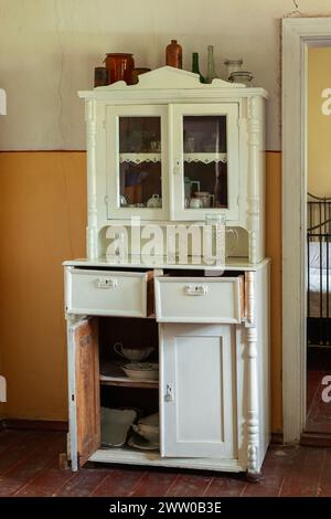 Armoire antique en bois de couleur blanche avec portes ouvertes pleines de vaisselle. Banque D'Images