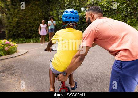 Père afro-américain apprend à son fils à faire du vélo à l'extérieur de la maison Banque D'Images