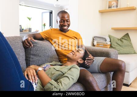 Un jeune couple afro-américain se détend sur un canapé confortable à la maison Banque D'Images