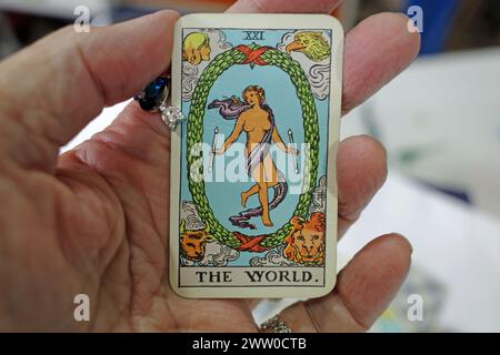 Main d'une diseuse de bonne fortune tenant une carte de tarot dans sa main. C'est le monde. Cette carte est synonyme de succès assuré, récompense, voyage, route, emigratio Banque D'Images