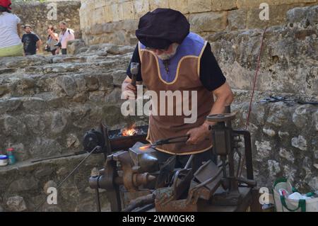 Herrero trabajando con martillo y fuego para dar forma al hierro. Banque D'Images