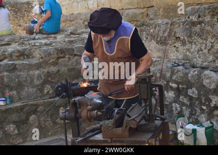 Herrero trabajando con martillo y fuego para dar forma al hierro. Banque D'Images