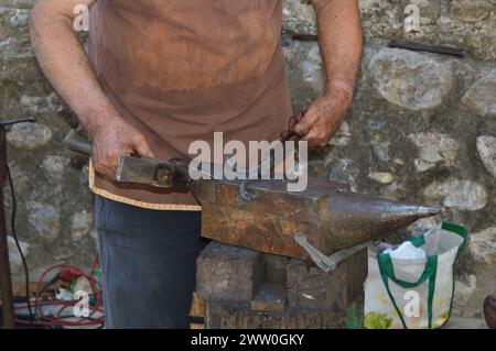 Herrero trabajando con martillo y fuego para dar forma al hierro. Banque D'Images