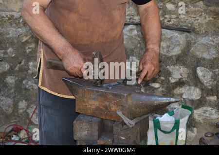 Herrero trabajando con martillo y fuego para dar forma al hierro. Banque D'Images