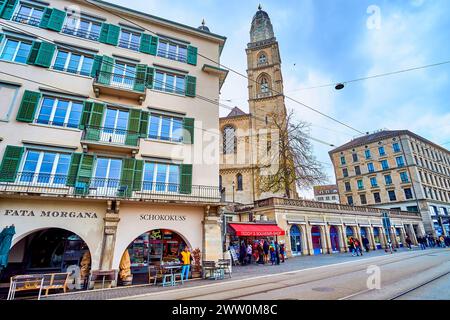 ZURICH, SUISSE - 3 AVRIL 2022 : la rangée de bâtiments médiévaux le long de la digue Limmatquai, avec l'impressionnante église Grossmunster dans le bac Banque D'Images