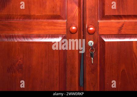 Image d'une clé insérée dans la serrure d'une armoire en bois, représentant la sécurité et la confidentialité Banque D'Images