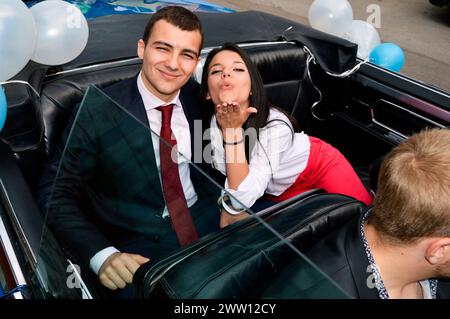 Heureux couples insouciants diplômés posant dans une voiture décapotable décorée de ballons avant d'aller à leur fête de bal à Sofia Bulgarie, Europe, UE Banque D'Images