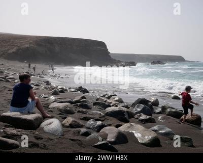 Ajuy plage scène de touristes sur le sable volcanique noir, Playa de Ajuí, Ajuy, Pajara, côte ouest de Fuerteventura, îles Canaries, Espagne Banque D'Images