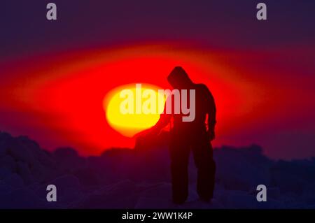 Inupiaq homme tient sa main sous le soleil de minuit dans la mer des Tchouktches, au large du village arctique de Barrow, Alaska Banque D'Images