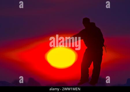 Inupiaq homme tient sa main sous le soleil de minuit dans la mer des Tchouktches, au large du village arctique de Barrow, Alaska Banque D'Images