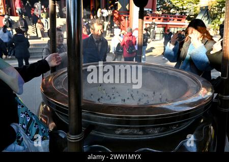 Les gens se sont rassemblés autour de brûleurs d’encens dans un Jokoro à l’intérieur du temple Sensō-ji – Asakusa, Taito City, Tokyo, Japon – 28 février 2024 Banque D'Images