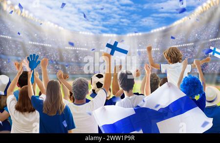 Joueur de football finlandais sur le stade. Fans finlandais sur un terrain de football regardant l'équipe jouer. Groupe de supporters avec drapeau et maillot national acclamant Banque D'Images