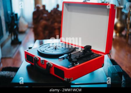 Plan large d'un tourne-disque vinyle portable rouge ouvert sur une surface en verre réfléchissante Banque D'Images