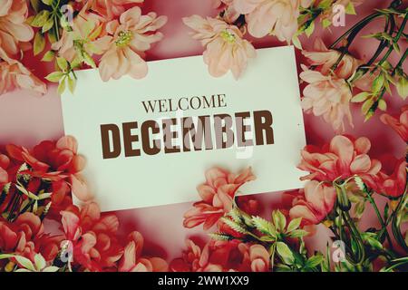 Bienvenue décembre texte typographique avec fleurs cadre sur fond rose Banque D'Images