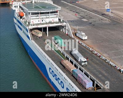 YANTAI, CHINE - 19 MARS 2024 - des camions sont entraînés dans un rouleau de chargement pour l'opération de déchargement à Yantai, province du Shandong, Chine, 19 mars 2024. Banque D'Images