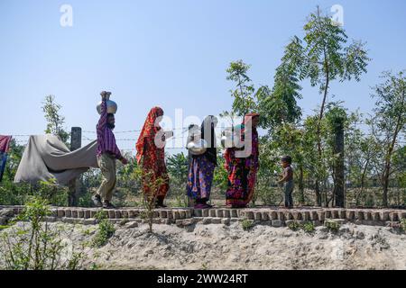 Dhaka, Bangladesh. 10 mars 2024. Personnes revenant de la collecte de l'eau potable d'un étang à Shyamnagar Gabura dans le district de Satkhira. À Gabura Union, dans le district de Shatkhira, dans le sud du Bangladesh, les habitants sont confrontés à une grave crise de l’eau potable exacerbée par le changement climatique. Les gens, y compris les femmes et les enfants, doivent parcourir quotidiennement de longues distances pour accéder à des sources d'eau salubre, ce qui augmente les risques sanitaires liés aux maladies d'origine hydrique. Les données au niveau des districts côtiers mettent en évidence des pourcentages significatifs aux prises avec des pénuries d'eau, les écologistes suggérant que la situation est plus grave. En déclin Banque D'Images