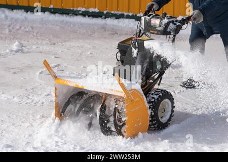 Opérateur ouvrier méconnaissable utilisant une souffleuse à neige pour enlever la neige après une tempête hivernale, assisté par une souffleuse à neige sur la route hivernale. L'ouvrier pelle la neige Banque D'Images