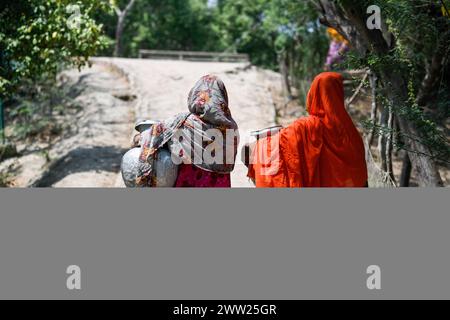 Dhaka, Bangladesh. 10 mars 2024. Les femmes reviennent de la collecte de l'eau potable d'une usine d'osmose inverse mise en place par une organisation non gouvernementale locale (ONG) à Shyamnagar Gabura, dans le district de Satkhira. À Gabura Union, dans le district de Shatkhira, dans le sud du Bangladesh, les habitants sont confrontés à une grave crise de l’eau potable exacerbée par le changement climatique. Les gens, y compris les femmes et les enfants, doivent parcourir quotidiennement de longues distances pour accéder à des sources d'eau salubre, ce qui augmente les risques sanitaires liés aux maladies d'origine hydrique. Les données au niveau des districts côtiers mettent en évidence des pourcentages importants aux prises avec des pénuries d'eau, Banque D'Images