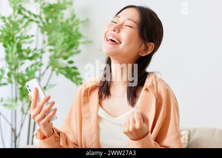 Femme asiatique riant en utilisant son téléphone portable Banque D'Images
