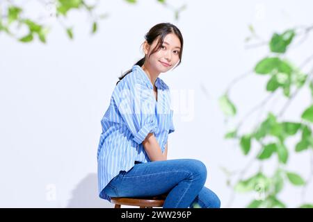 Une femme assise sur un tabouret les jambes croisées Banque D'Images