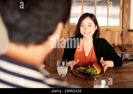 Une femme assise à une table avec un sandwich et un verre d'eau Banque D'Images