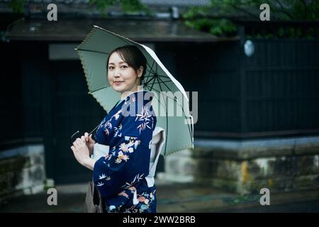 Une femme en kimono tenant un parapluie Banque D'Images