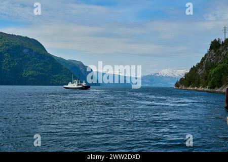 Ferry norvégien typique traversant un beau fjord entre les montagnes transportant des passagers et des voitures sur le chemin de Geiranger par une journée ensoleillée, Banque D'Images