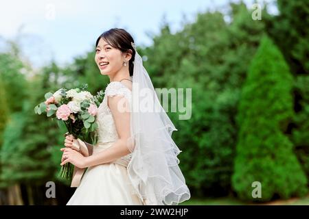 Une mariée dans une robe de mariée tenant un bouquet Banque D'Images