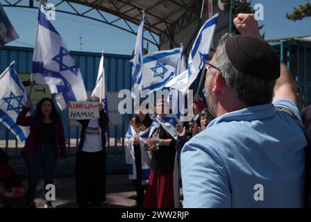 Des militants de droite tiennent des drapeaux et des pancartes israéliens alors qu’ils scandent des slogans lors d’une manifestation devant le bureau de l’UNRWA, appelant à l’expulsion du bureau de l’UNRWA de la ville le 20 mars 2024 à Jérusalem. Israël Banque D'Images