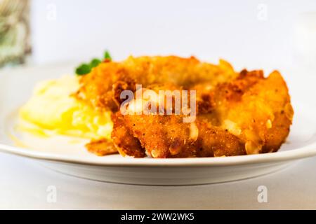 Schnitzel frit dans de la chapelure avec des amandes, purée de pommes de terre sur plaque blanche, gros plan. Banque D'Images