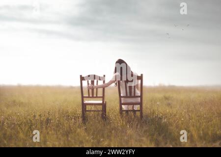 femme triste regarde nostalgiquement la chaise vide de son amant au milieu de la nature Banque D'Images