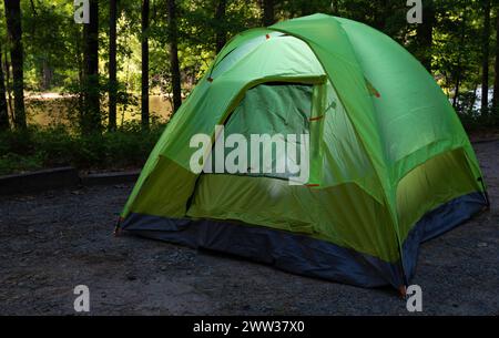 Tente de sac à dos de deux hommes dans un camping avec des lumières à l'intérieur et le lac à la lumière du soleil derrière. Banque D'Images