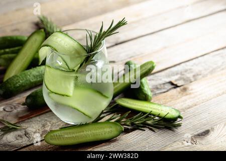 Gin tonique avec des tranches de glace, de romarin et de concombre en verre dépoli. Cocktail avec ingrédients sur une ancienne table en bois. Copier l'espace. Banque D'Images
