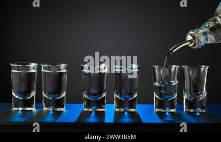Doses alcoolisées de vodka ou de boisson forte dans de petits verres. Barman versant de l'alcool dur dans des verres en détail, concept sur le service et les boissons. COP Banque D'Images