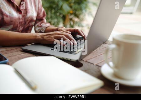 Gros plan de la femme travaillant sur l'ordinateur portable à la table de coffeeshop extérieure Banque D'Images