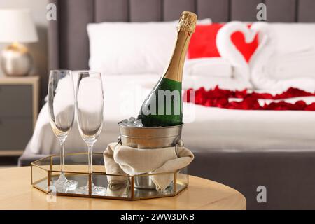 Lune de miel. Vin mousseux et verres sur la table en bois dans la chambre Banque D'Images