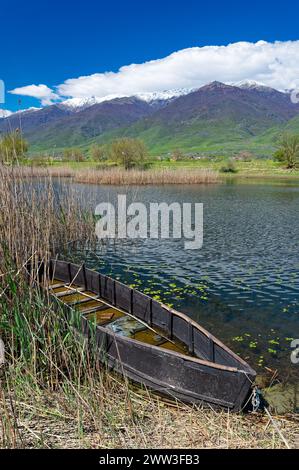 Avis de Kerkini Lake dans le nord de la Grèce avec bateau de pêche en bois traditionnel et d'une partie du mont enneigé Beles Banque D'Images