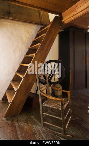 Fauteuil à bascule antique et roue tournante à côté des escaliers de Miller dans la chambre principale à l'étage menant au grenier à l'intérieur de la vieille maison de 1785, Québec Banque D'Images