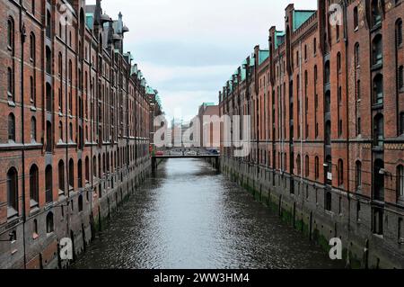 Vue d'un canal d'eau calme entouré de bâtiments symétriques en briques sous un ciel nuageux, Hambourg, ville hanséatique de Hambourg, Allemagne Banque D'Images