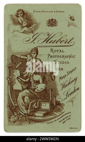 Revers de charmante carte de visite victorienne originale très décorative (carte de visite ou CDV) avec chérubin et design d'artiste. Du studio photographique royal de Joseph Hubert, rue Mare, Hackney. Circa 1888, 1889, 1890 / 1890 Banque D'Images