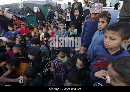 Des enfants palestiniens regardent des dessins animés à l'écran dans un camp d'hébergement à l'intérieur de l'hôpital des martyrs d'Al-Aqsa des enfants palestiniens regardent des dessins animés à l'écran dans un camp d'hébergement à l'intérieur de l'hôpital des martyrs d'Al-Aqsa à Deir Al-Balah, le 21 mars 2024. Les États-Unis et d'autres pays médiateurs des pourparlers de cessez-le-feu entre Israël et le Hamas espéraient parvenir à une trêve temporaire avant le début du mois sacré islamique, mais les récentes réunions au Caire n'ont pas abouti. Pendant ce temps, la situation humanitaire reste désastreuse à Gaza, les pays étrangers proposant de nouveaux moyens d’accroître les livraisons d’aide, comme le crea Banque D'Images