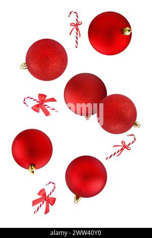 Boules de Noël rouges et cannes de bonbons tombant sur fond blanc Banque D'Images