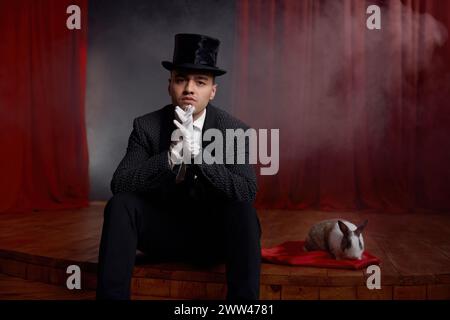 Showman pensif en costume assis sur la scène de théâtre se reposant après le spectacle de magie Banque D'Images